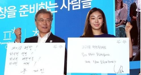 President Moon Jae-in (L) and former Olympic figure skating champion Kim Yu-na, both honorary ambassadors for the 2018 PyeongChang Winter Olympic Games, hold up their hand-written messages wishing for the country's successful hosting of the event in a ceremony held in PyeongChang, 180 kilometers east of Seoul, on July 24, 2017. (Yonhap)