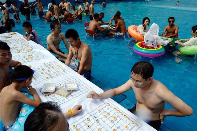 <YONHAP PHOTO-3707> People play Chinese chess in a pool to escape the hot weather in Chongqing, southwest China on August 2, 2017. A red alert for high temperatures was issued on August 2 as temperatures reached 40 degrees in Chongqing. / AFP PHOTO / STR / China OUT/2017-08-02 20:01:22/ <저작권자 ⓒ 1980-2017 ㈜연합뉴스. 무단 전재 재배포 금지.>