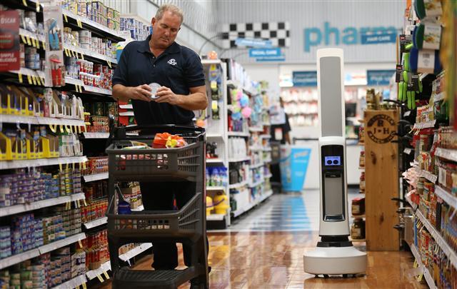 <YONHAP PHOTO-1636> Shopper John Patrick reads the label on a can as Tally the robot checks the inventory in the Mexican food isle at the Schnucks Supermarket in Richmond Heights, Missouri on August 7, 2017. The 30-pound robot is equipped with sensors to help it navigate through the store,detecting product that is not fully stocked. That data is sent to store management so changes can be made. Tally will be tested over six weeks. Photo by Bill Greenblatt/UPI/2017-08-08 06:58:04/ <저작권자 ⓒ 1980-2017 ㈜연합뉴스. 무단 전재 재배포 금지.>