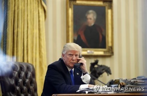 US President Donald Trump on the phone in the Oval Office of the White House in Washington on Jan. 28, 2017. (AP-Yonhap)