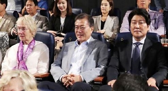 President Moon Jae-in (C) flanked by Edeltraut Brahmstaedt (L) and actor Song Kang-ho watch the movie "A Taxi Driver" at a movie theater in Seoul on Aug. 13, 2017. (Yonhap)