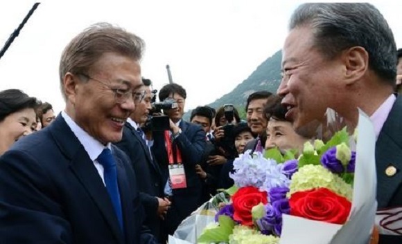 President Moon Jae-in (L) receives welcome flowers from his new neighbors who live near the presidential office Cheong Wa Dae in Seoul on May 10, 2017, the day he was sworn in South Korea's new president after winning the presidential by-election held the previous day. (Yonhap)