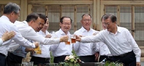 The file photo, taken July 27, 2017, shows President Moon Jae-in (R) toasting a group of top local business leaders in a meeting held at the presidential office Cheong Wa Dae to listen to their views on his new economic initiatives, as well as ask for their support in his plan to create more than 1 million new jobs during his single five-year presidency. (Yonhap)