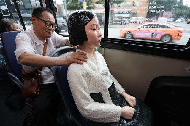 <YONHAP PHOTO-1978> '고생 많으셨습니다' (서울=연합뉴스) 김현태 기자 = 14일 오전 서울 시내버스 151번을 탄 한 시민이 버스에 설치된 평화의 소녀상의 어깨를 주물러 주고 있다. 151번 버스를 운영하는 동아운수 측은 아이들에게 올바른 역사의식을 가질 수 있는 계기를 마련하고자 세계 위안부 기림일인 14일부터 9월 30일까지 151번 버스 5대에 소녀상을 설치해 운행한다고 밝혔다. 2017.8.14 mtkht@yna.co.kr/2017-08-14 07:28:41/ <저작권자 ⓒ 1980-2017 ㈜연합뉴스. 무단 전재 재배포 금지.>