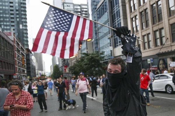 A person burns an American flag Sunday, Aug. 13, 2017, in Seattle. Hundreds of demonstrators and counter-protesters converged in downtown Seattle one day after violent clashes in Charlottesville, VA. (AP)