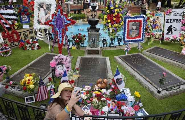A fan takes a photo of herself at the Meditation Garden where Elvis Presley is buried alongside his parents and grandmother at his Graceland mansion on Saturday in Memphis, Tennessee. (AFP-Yonhap)