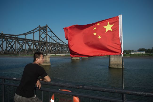 This file picture taken on July 6, 2017 shows a tourist looking out from the Broken Bridge next to the Friendship bridge on the Yalu River connecting the North Korean town of Sinuiju and the Chinese border city of Dandong. (AFP via Yonhap)