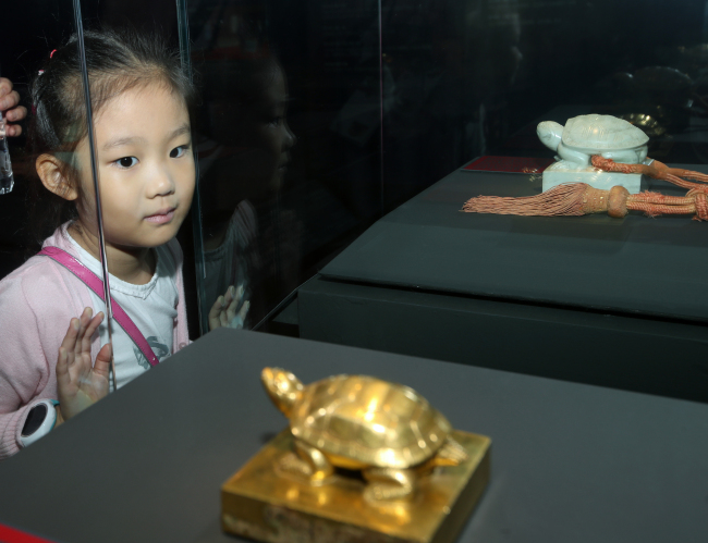 A child looks at the Golden Royal Seal for the Bestowal of Honorific Title upon Queen Munjeong on display at National Palace Museum of Korea on last Friday, while Royal Seal of King Hyeonjong is seen at the rear. (Yonhap)