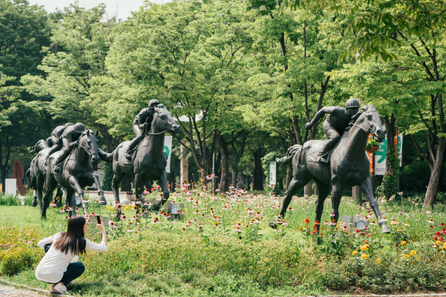Deer, statues and a bench are seen at forests in Seoul.