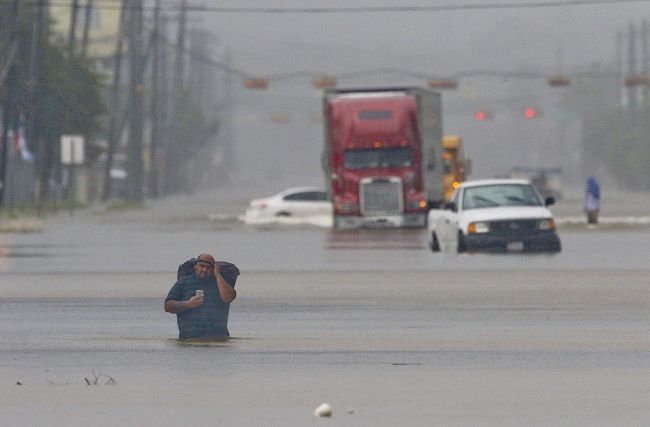 A man carries his belonging as he walks through the flooded waters in Houston on Sunday as the US fourth city city battles with tropical storm Harvey and resulting floods. (AFP-Yonhap)