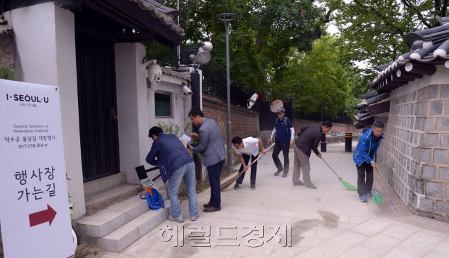 서울시 직원들이 30일 새롭게 개방한 덕수궁 돌담길을 청소하고 있다. 왼편에 기와를 올린 철대문은 영국대사관이 새로 설치한 후문이다. 시민들은 덕수궁을 돌아 돌담길로 빠져서 광화문 쪽으로 이동할수 있다. [사진=정희조 기자/checho@heraldcorp.com]