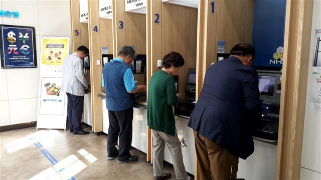서울 종로구의 한 은행 현금자동입출금기(ATM)에서 금융업무를 보고 있는 노인들.