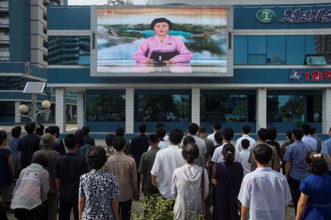 Pyongyang residents watch a video screen showing a newsreader announcing that the country has successfully tested a hydrogen bomb on Sunday. (AFP-Yonhap)