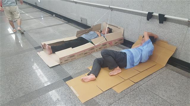 서울 중구 지하철 1ㆍ4호선 서울역 6ㆍ7번 출구 통로에서 두 노숙인이 종이박스를 깔고 누워있다.