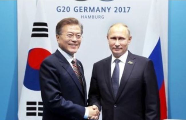 This file photo taken on July 7, 2017, shows South Korean President Moon Jae-in (L) shaking hands with Russian President Vladimir Putin in Germany. (Yonhap)