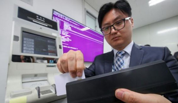 A police officer demonstrates the process of copying a credit card during a press briefing on the ATM hacking case in Seoul on Sept. 6, 2017. (Yonhap)