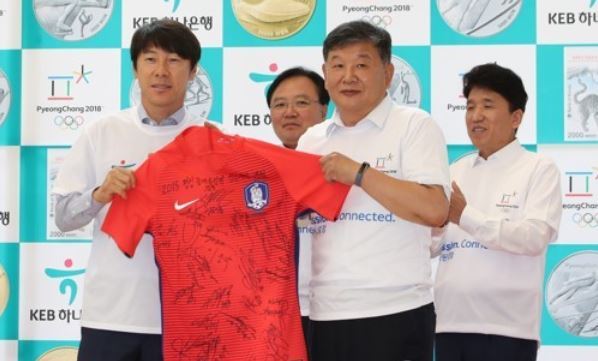 South Korea's national football team head coach Shin Tae-yong (L) holds the national football team jersey with Roh Tae-kang, the second vice minister of the Ministry of Culture, Sports and Tourism, at an event to promote reservations of commemorative coins for the 2018 PyeongChang Olympics at the KEB Hana Bank headquarters in Seoul on Sept. 11, 2017. (Yonhap)