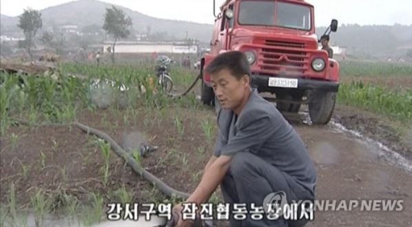 A North Korean man waters a dried-up field by mobilizing a fire truck during a severe drought in this photo captured from the North's Korean Central TV on June 26, 2017. (For Use Only in the Republic of Korea. No Redistribution) (Yonhap)