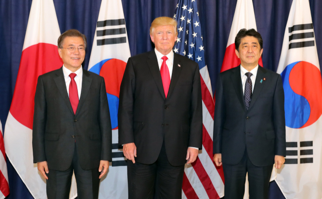 President Moon Jae-in, US President Donald Trump and Japanese Prime Minister Shinzo Abe (from L to R) pose for a photo during a trilateral meeting held in July on the sidelines of a Group of 20 summit. (Yonhap)