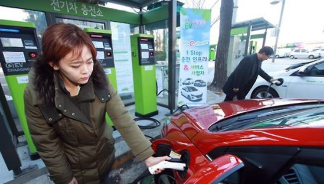 In this Yonhap file photo, a woman charges her electric car using a charger set up in Gwanghwamun, central Seoul. (Yonhap)