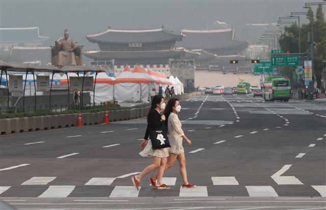 중국발 미세먼지를 막아주던 태풍 탈림이 소멸되니 모처럼 청명했던 가을 하늘에 다시 미세먼지가 찾아왔다. 이번 미세먼지는 일시적이지만 10월부터는 다시 가을철 미세먼지가 기승을 부릴 가능성이 크다. 사진은 전국 곳곳에서 미세먼지 농도가 ‘한때 나쁨’을 보인 19일 오전 서울 광화문역 인근에서 시민들이 길을 건너고 있다.  [연합뉴스]