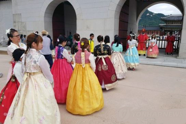 A group of foreign tourists wearing traditional Korean costumes wait in line to take photos with palace guards in front of the main gate of Gyeongbok Palace in Seoul on Aug. 17, 2017. (Yonhap)