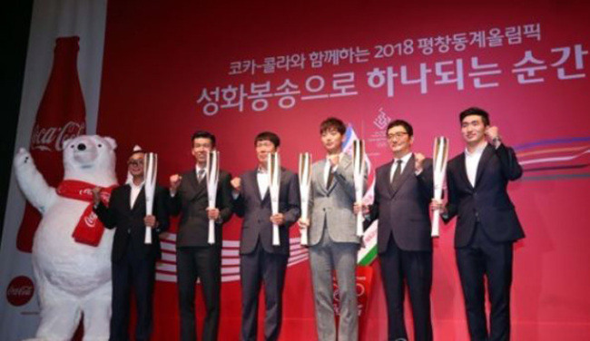 Torch runners for the 2018 PyeongChang Winter Olympics pose with the torches at a ceremony held in Seoul on Sept. 27, 2017. From left: former marathon Olympic silver medalist Lee Bong-joo; singer Sean; former football star Cha Bum-kun; singer Jeong Jin-woon; photographer Cho Sei-hon; and fencer Park Sang-young. (Yonhap)