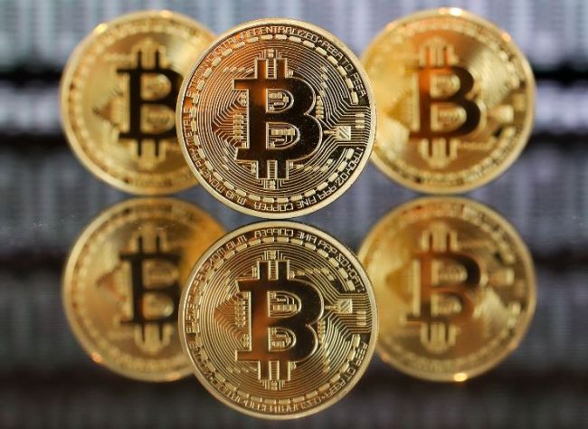 A collection of bitcoin tokens stand in front of an illustration of binary code in this arranged photograph taken in London on Jan. 4. (Bloomberg)