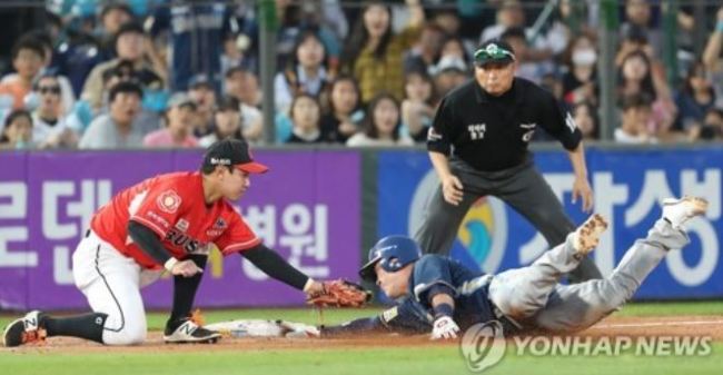 NC Dinos' Ji Seok-hun (R) slides into third base safely after a wild pitch by Lotte Giants' Park Si-young in the top of the 11th inning in Game 1 of the clubs' first round postseason series in the Korea Baseball Organization at Sajik Stadium in Busan on Oct. 8, 2017. The Dinos went on to take the game 9-2. (Yonhap)