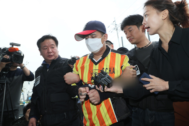 A murder suspect is escorted into a police station in northeastern Seoul on Tuesday, to undergo questioning over suspicions he killed a friend of his daughter and abandoned her body. (Yonhap)