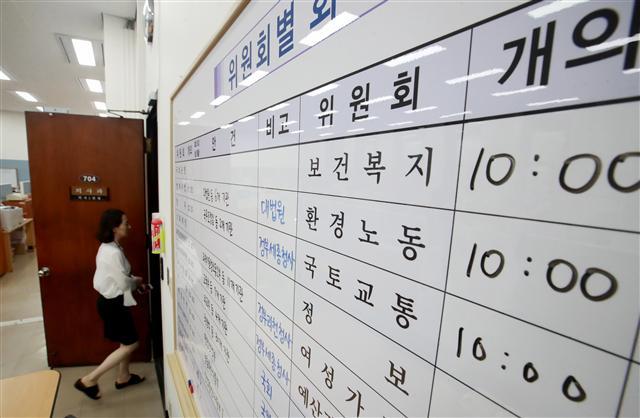 2017년도 국정감사를 하루 앞둔 11일 오전 서울 여의도 국회 본청 의사과에서 직원들이 국정감사 첫날 상임위원회별 감사 일정이 적힌 현황판 앞을 지나고 있다. 	 [연합뉴스]