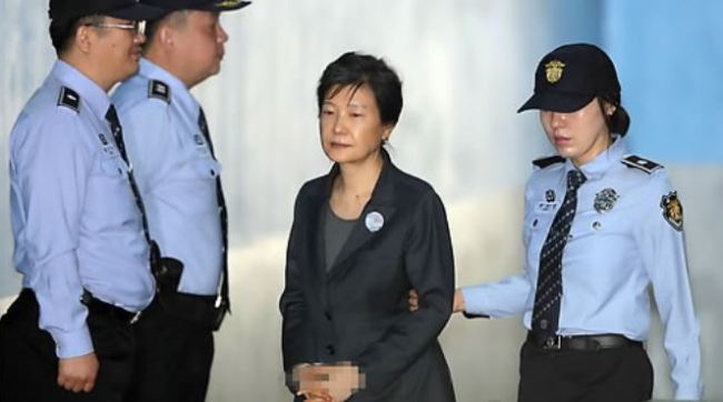 Former President Park Geun-hye is escorted by a guard as she arrives at the courthouse in southern Seoul to attend trial in a bribery and corruption case on Oct. 10, 2017. (Yonhap)