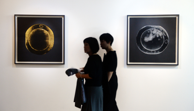 Visitors pass by works by El Anatsui on display at “El Anatsui: Topology of Generosity” on Sept. 26. (Park Hyun-koo/The Korea Herald)