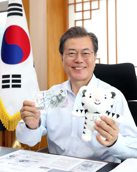 문재인 대통령이 13일 오후 청와대 여민관 집무실에서 ‘평창동계올림픽 기념은행권’에 서명한 뒤 은행권과 올림픽 마스코트 인형을 들어보이고 있다. [사진제공=청와대]