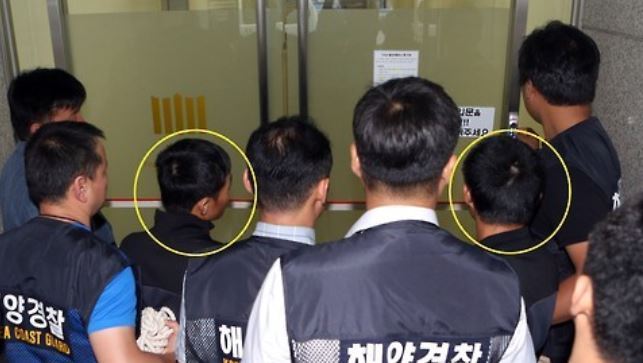 Two Vietnamese men (circled) arriving in a court in the southeastern city of Busan to attend a hearing to review the legality of their detention over the murder of two South Koreans. (Yonhap)