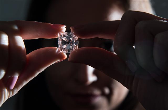 <YONHAP PHOTO-1832> A woman poses with the 'Le Grand Mazarin', a 19.07 carat pink diamond, at Christie's auction house in London on October 17, 2017. 'Le Grand Mazarin' is estimated to reach 6-9 million dollars on auction in Geneva on November 14, 2017. / AFP PHOTO / CHRIS J RATCLIFFE/2017-10-18 08:39:58/ <저작권자 ⓒ 1980-2017 ㈜연합뉴스. 무단 전재 재배포 금지.>