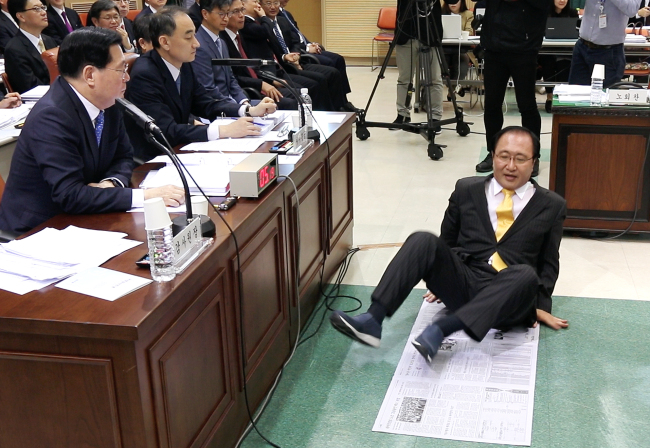 Rep. Roh Hoe-chan of the minor Justice Party demonstrates the average floor space available to ordinary inmates at South Korean detention facilities, about the size of five pages of a broadsheet newspaper, in relation to claims that former President Park Geun-hye is subjected to poor conditions in custody during the parliamentary audit of the Board of Audit and Inspection in Seoul on Thursday. Yonhap
