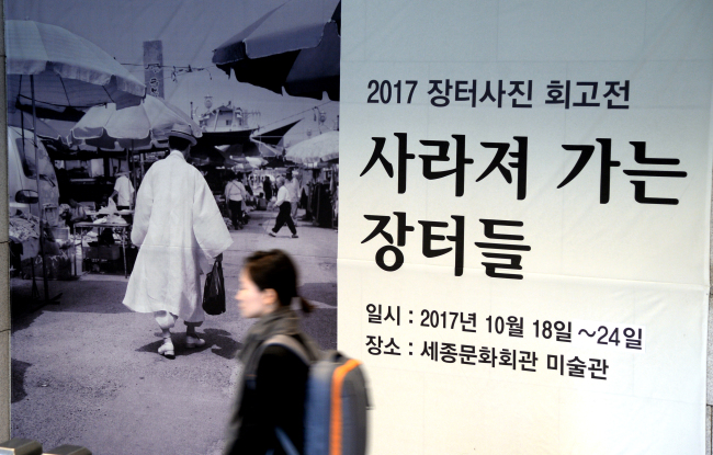 Visitors look at the photos of traditional marketplaces taken by Jangteo Photo Club at Sejong Center for the Performing Arts in Seoul on Friday. (Park Hyun-koo/The Korea Herald)