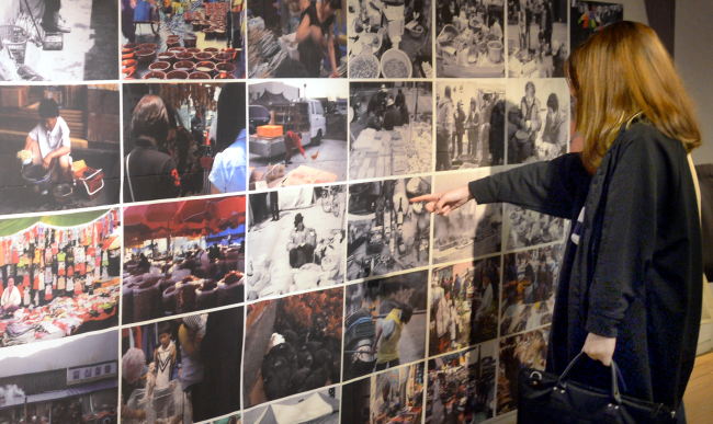 Visitors look at the photos of traditional marketplaces taken by Jangteo Photo Club at Sejong Center for the Performing Arts in Seoul on Friday. (Park Hyun-koo/The Korea Herald)