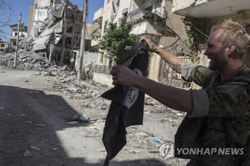 'IS 수도' 락까에서 IS기를 불태우는 SDF 대원(사진=AP-연합뉴스)