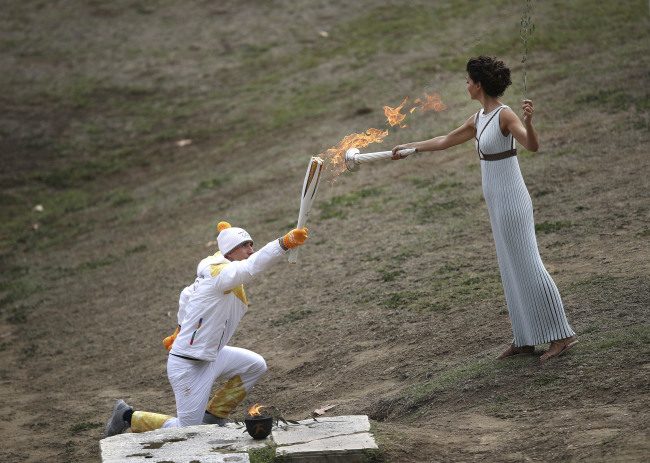 Actress Katerina Lehou as high priestess, right, lights the torch of bearer Greek cross-country skier Apostolos Angelis during the lighting ceremony of the Olympic flame in Ancient Olympia, southwestern Greece, on Tuesday, Oct. 24, 2017. The flame will be transported by torch relay to Pyeongchang, South Korea, which will host the Feb. 9-25, 2018 Winter Olympics. (AP-Yonhap)