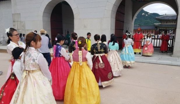 A group of foreign tourists wearing traditional Korean costumes wait in line to take photos with palace guards in front of the main gate of Gyeongbok Palace in Seoul on Aug. 17, 2017.