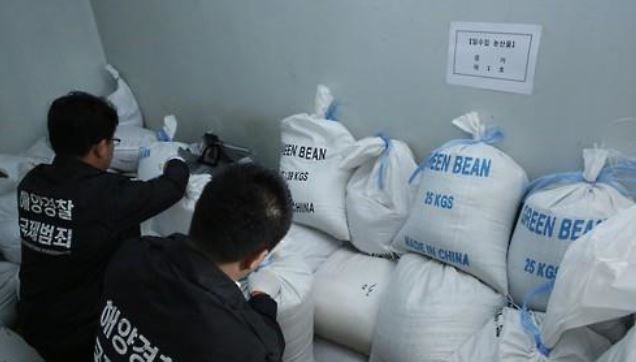 This undated file photo shows agents of the Coast Guard securing beans smuggled from China. (Yonhap)