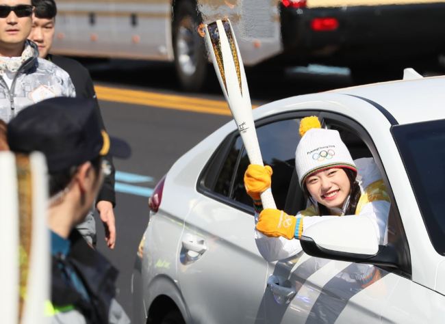 K-pop singer Kim So-hye carried the Olympic flame in the Jeju Island leg of torch relay riding in and IONIQ electric vehicle from Hyundai Motor on Thursday. (Yonhap)