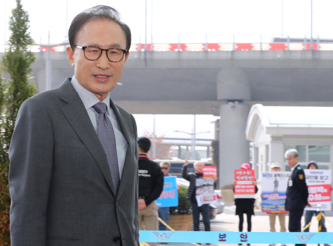 이명박 전 대통령이 지난 12일 바레인으로 출국하기 위해 인천공항에 도착하는 모습. 그 뒤로 이 전 대통령 구속을 촉구하는 시위가 열리고 있다. [사진제공=연합뉴스]