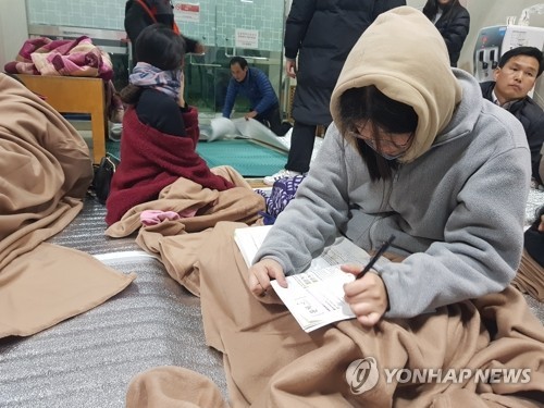 15일 경북 포항에서 규모 5.4 지진이 발생한 뒤 주민들이 대피한 북구 흥해실내체육관에서 한 고3 학생이 수능시험 공부를 하고 있다. (사진=연합뉴스)