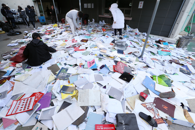 Students rummage through a pile of study aids discarded to mark the end of their preparations in Seoul on Thursday. Yonhap