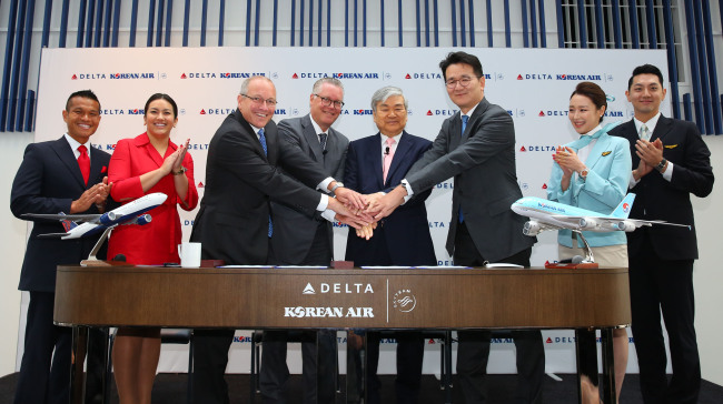 Hanjin Group Chairman Cho Yang-ho (fourth from right), Korean Air President Cho Won-tae (third from right), Delta Air Lines CEO Ed Bastian (fourth from left), and Delta Air Lines President of International Steve Sear (third from left) hold hands at an event held to celebrate the joint venture between the two carriers, at the Wilshire Grand Center in Los Angeles on Jun. 23. (Korean Air)
