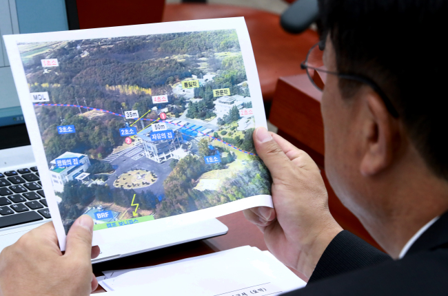 A lawmaker studies the aerial shot of the Joint Security Area, through which a North Korean soldier defected sustaining gunshot wounds. (Yonhap)
