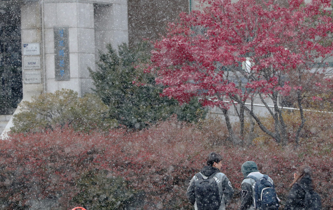Snow falls despite the leaves not having fallen yet (Yonhap)